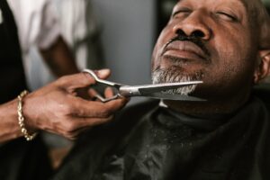 person cutting man s beard